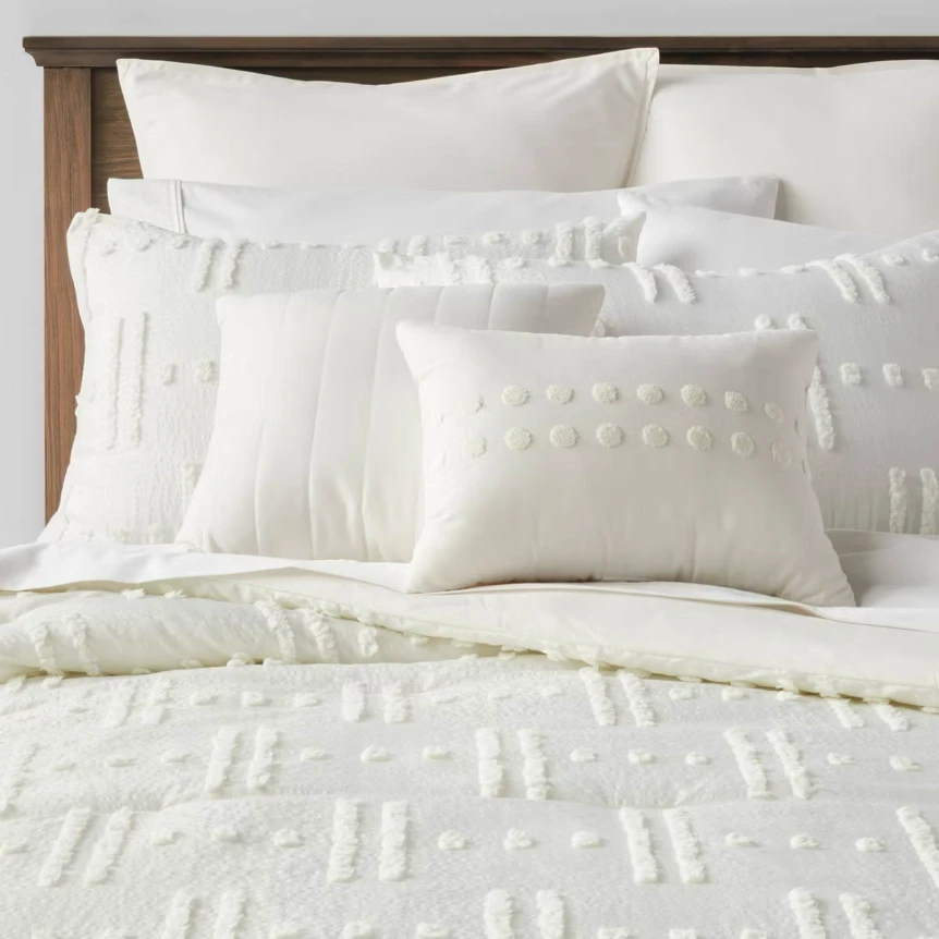 White textured bedding set with tufted duvet cover and matching pillows on wooden bed frame