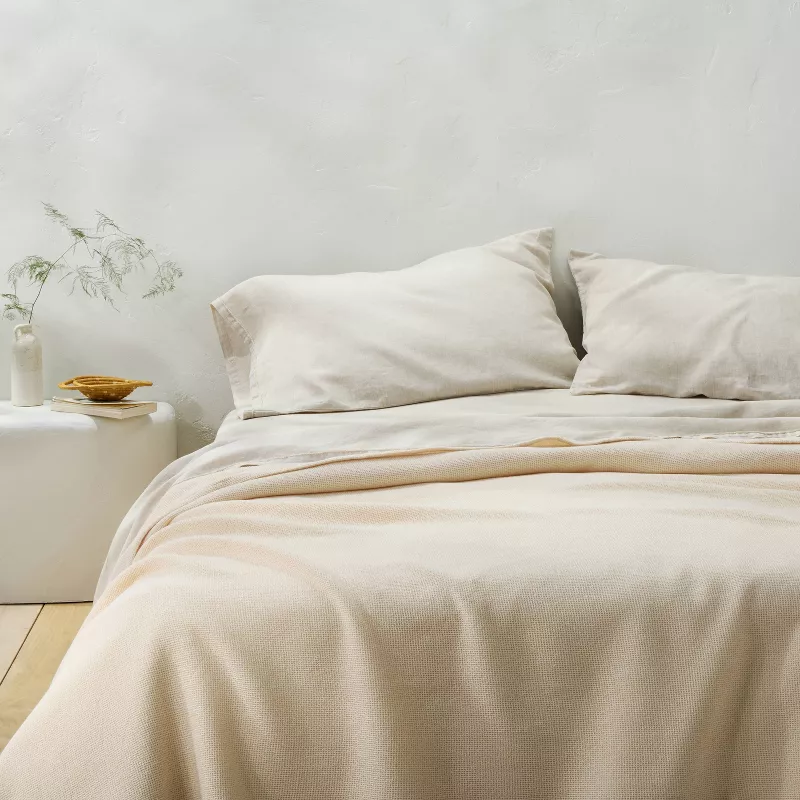Full/Queen Micro Waffle Bed Blanket in Natural cream color draped over white bedding with pillows