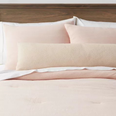 Lumbar boucle colorblock throw pillow on bed with blush pink bedding and wooden headboard