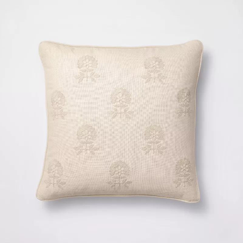 Cream pillow with embroidered floral medallion pattern on white background