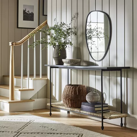 Modern entryway with black metal console table, oval mirror, brass stair railing, and coastal farmhouse decor