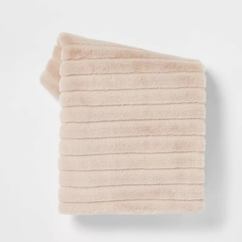 Textured faux fur reversible throw blanket in neutral beige with ribbed pattern folded on white background