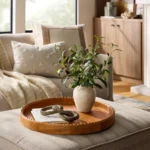 Realistic faux plant in ceramic vase on wooden tray with decorative items on coffee table in modern living room
