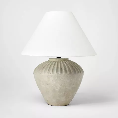 Ceramic table lamp with ribbed tan base and white conical shade on neutral background