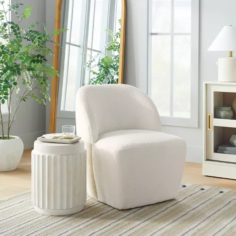 Cream boucle swivel accent chair in bright living room with white side table and natural light from windows
