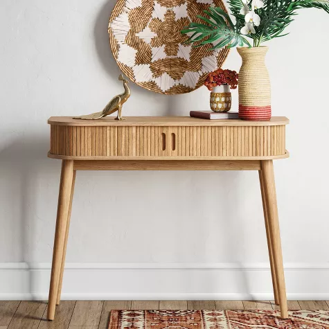 Mid-century modern wooden console table with drawer in entryway featuring decorative mirror and plants