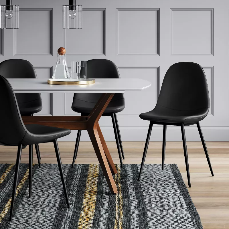 Modern dining table set with white round table and black upholstered chairs on patterned rug