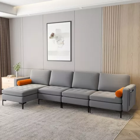 Modern gray L-shaped sectional sofa with chaise lounge and orange pillows in contemporary living room