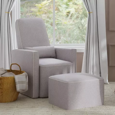 Gray upholstered nursery glider chair with matching ottoman beside window with white curtains and wicker basket