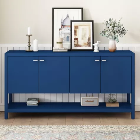 Blue console table with four doors and lower shelf, styled with frames and decor in modern entryway