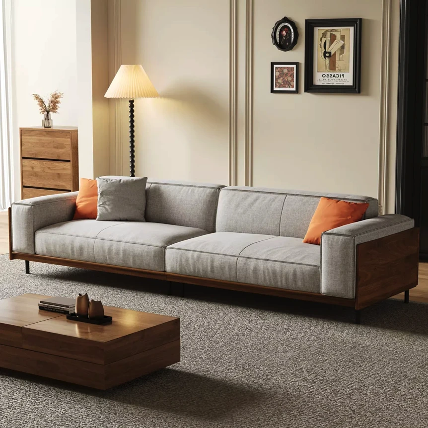 Modern gray sofa with orange pillows in warm living room with wooden furniture and neutral decor