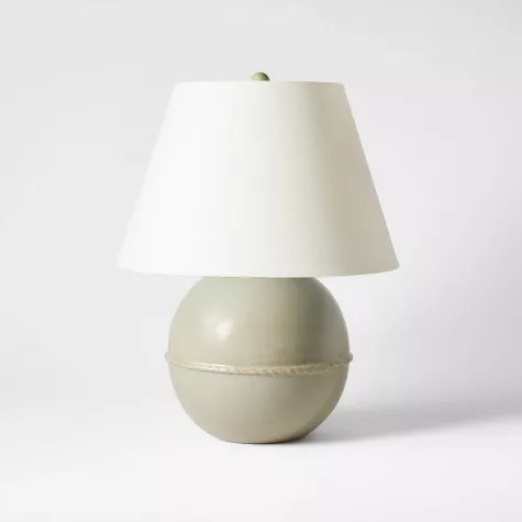 Medium ceramic table lamp with spherical green base and white tapered shade on neutral background