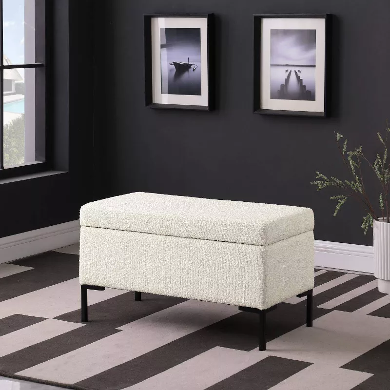 White upholstered storage bench with black legs on striped rug in modern dark gray room with framed artwork