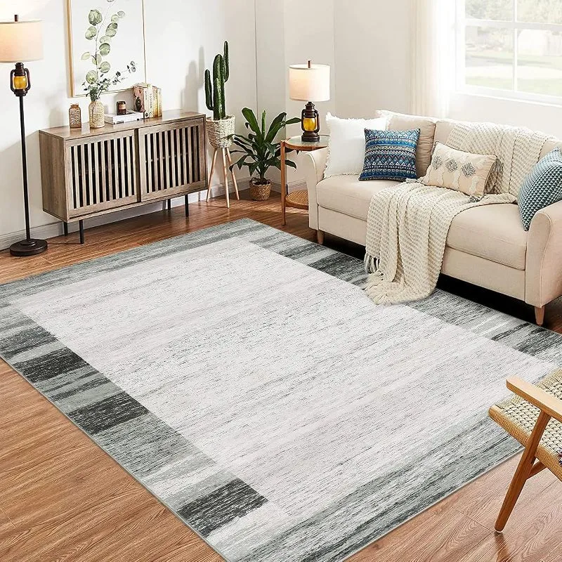 Modern bordered area rug with gray and white stripes in contemporary living room with beige sofa and wood floor