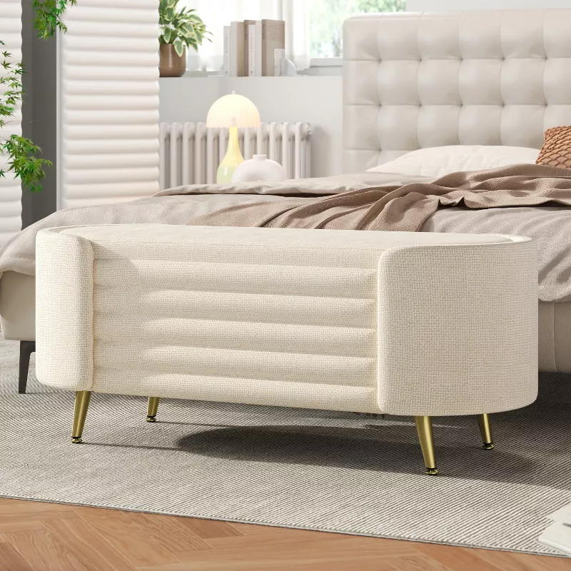 Modern upholstered storage bench with channel tufting and gold legs at foot of bed in contemporary bedroom