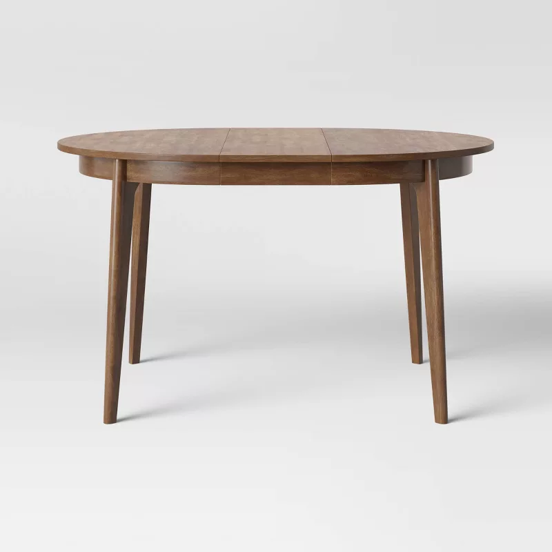 Round wooden dining table with tapered legs in natural finish on white background