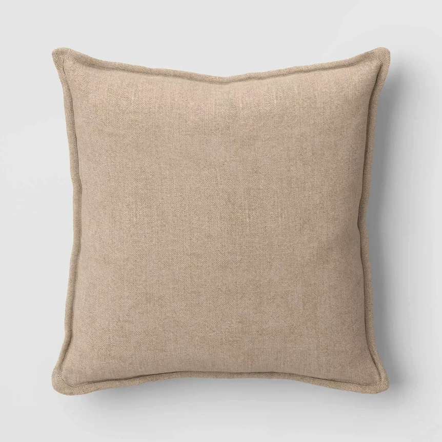 Neutral beige linen throw pillow with piped edges on white background for elegant home decor