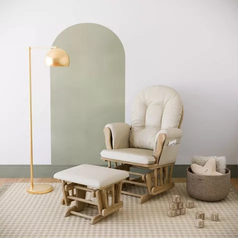 Beige glider chair with ottoman in modern nursery featuring sage green arch accent wall and neutral decor