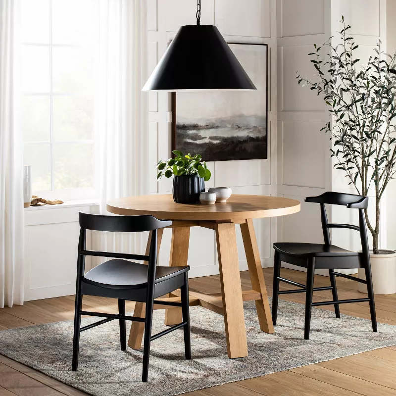 Round wood dining table with black chairs and pendant light in modern minimalist dining room