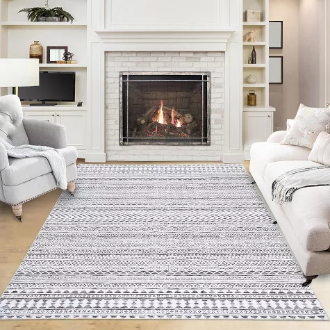 White and gray patterned washable area rug in modern living room with fireplace and light furniture