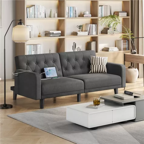 Modern gray tufted convertible sofa in contemporary living room with white coffee table and wooden bookshelf
