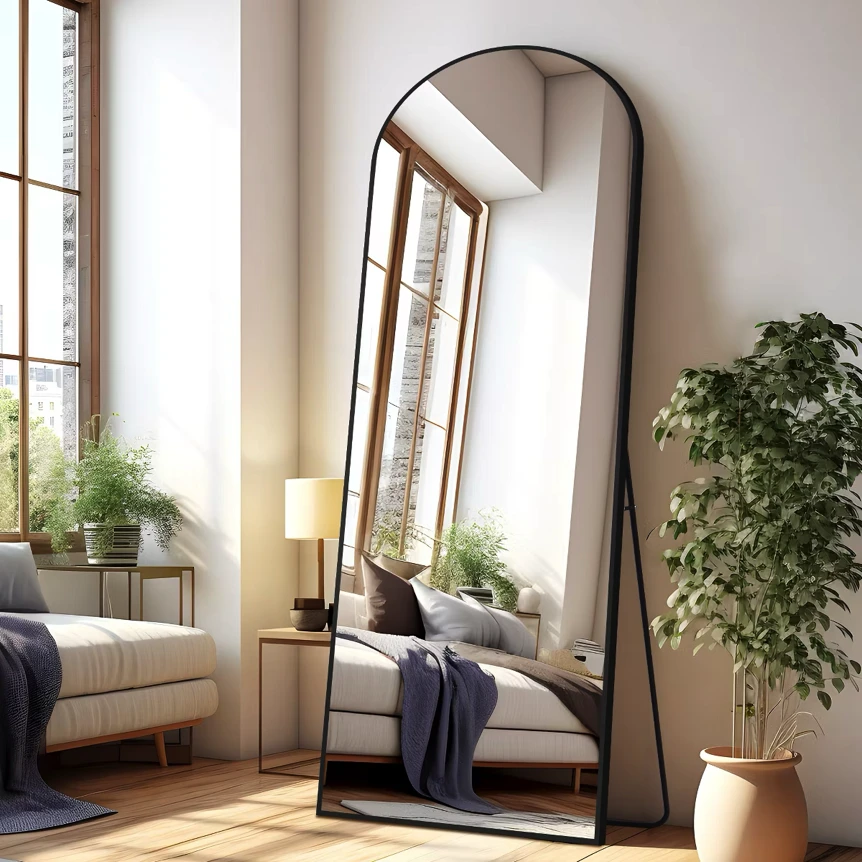 Large arched full length mirror with metal frame in minimalist bedroom with natural light and plants