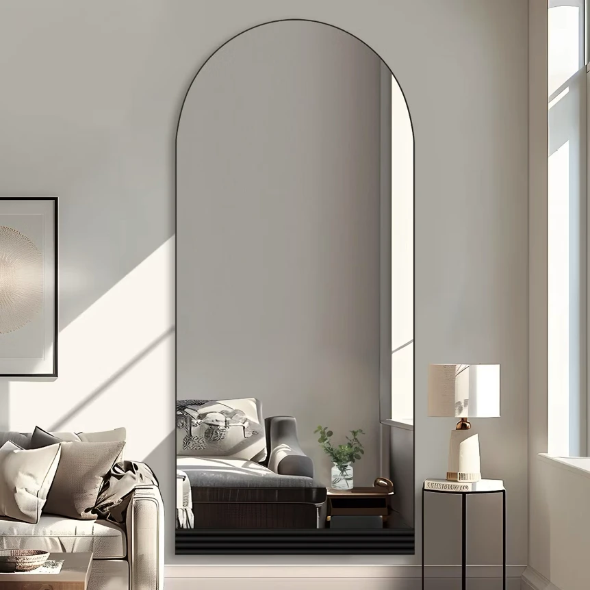 Large arched floor mirror in modern living room with neutral decor and natural light