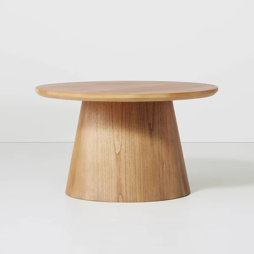 Wooden round pedestal coffee table with natural oak finish and conical base against white background