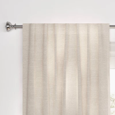 Cream textured blackout curtain panel hanging on silver rod against white wall