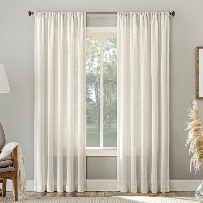 Ivory sheer curtain panels with rod pocket hanging on window, showing light filtering fabric in neutral living room