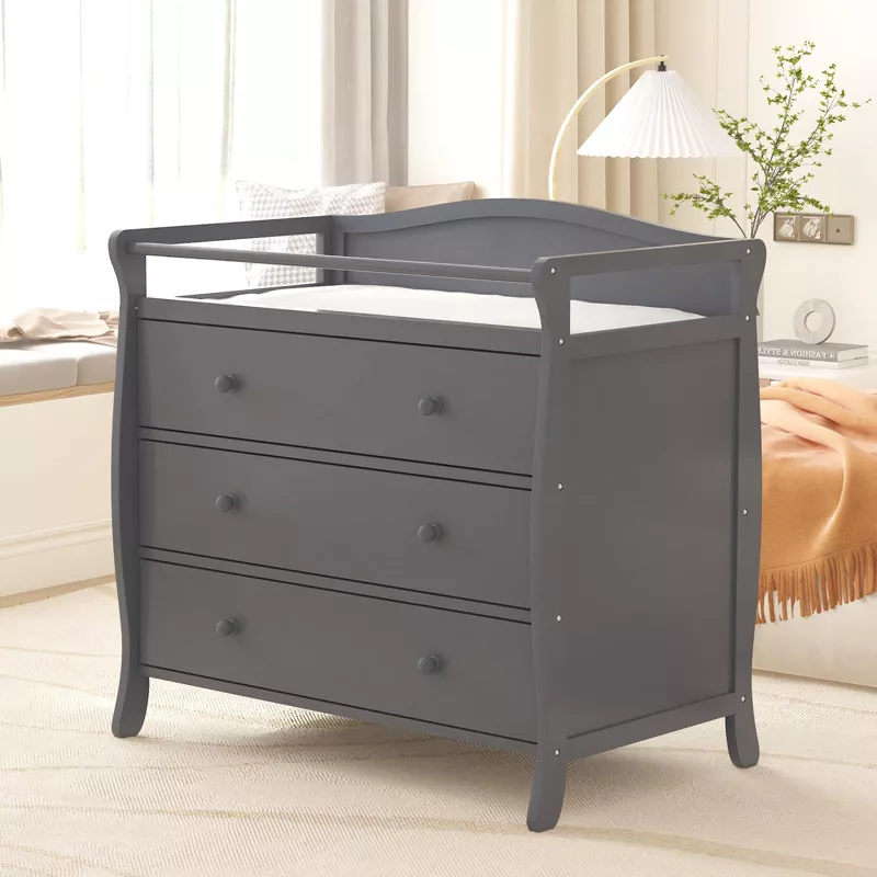 Gray wooden changing table with three drawers and safety rail in modern nursery bedroom