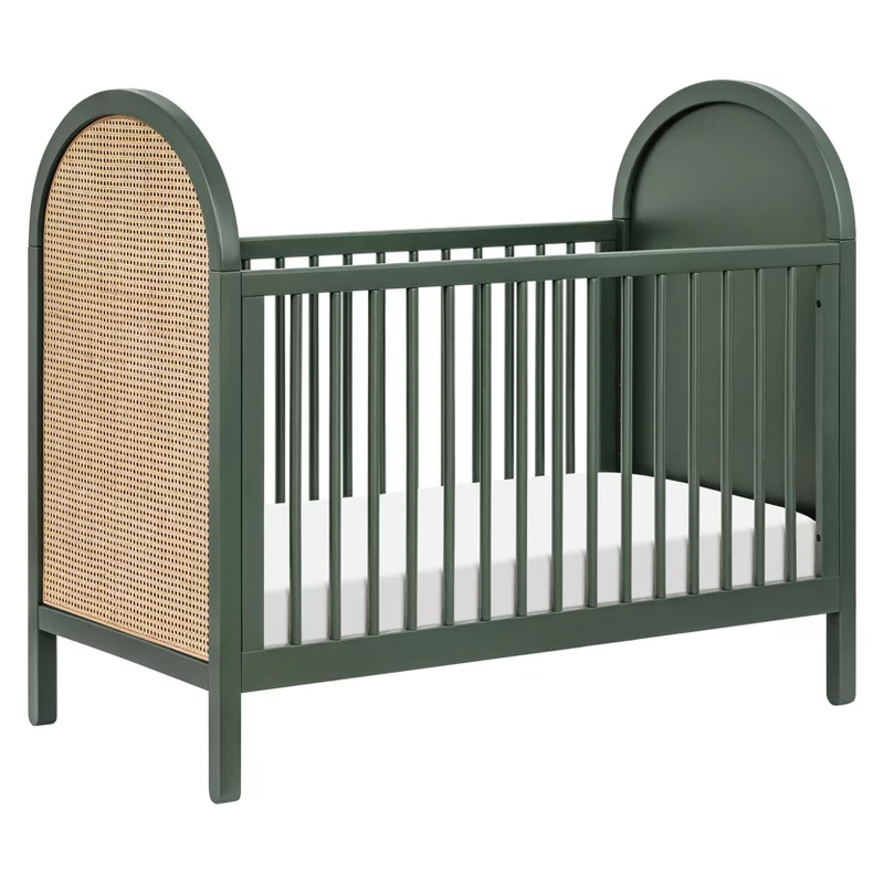 Green wooden crib with natural rattan panels and arched headboard for nursery bedroom