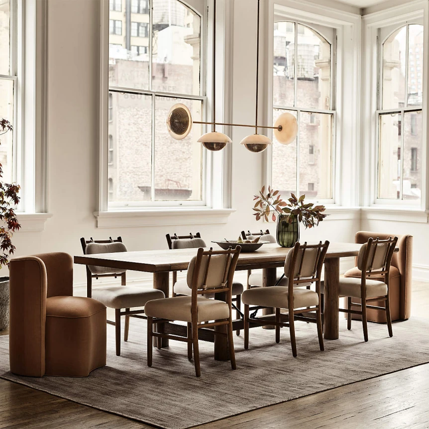 Modern dining room with mismatched brown chairs around white table featuring large windows and pendant lighting