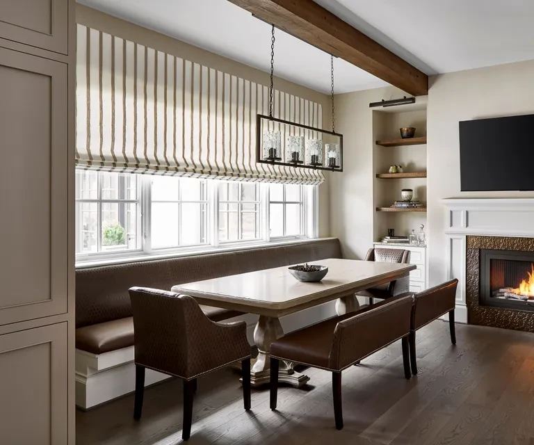 Modern dining room with wooden table, built-in bench seating, pendant light, and striped window shade