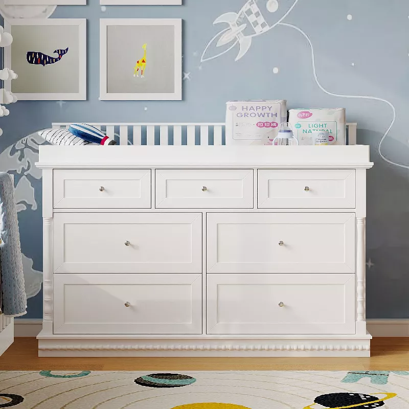 White changing table dresser with multiple drawers in nursery with space-themed wall decor and wooden floor