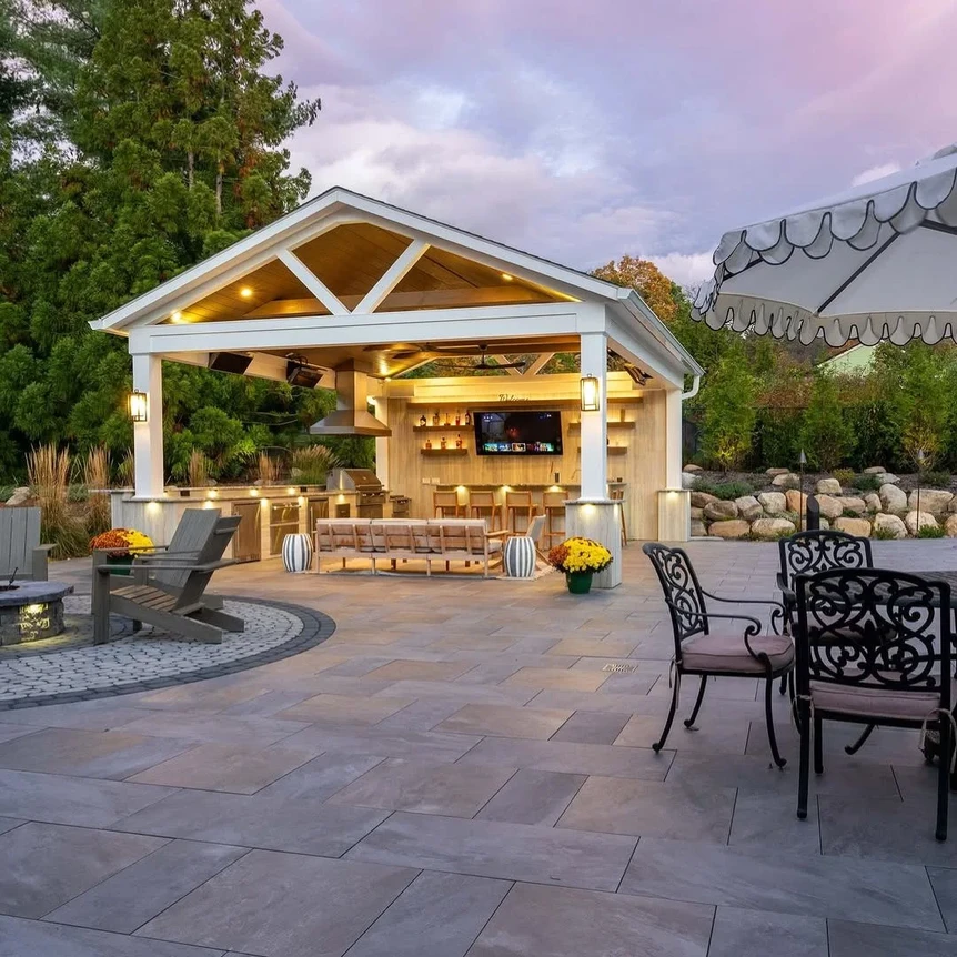 Luxury outdoor patio with covered pavilion, stone flooring, built-in kitchen, and elegant metal dining furniture