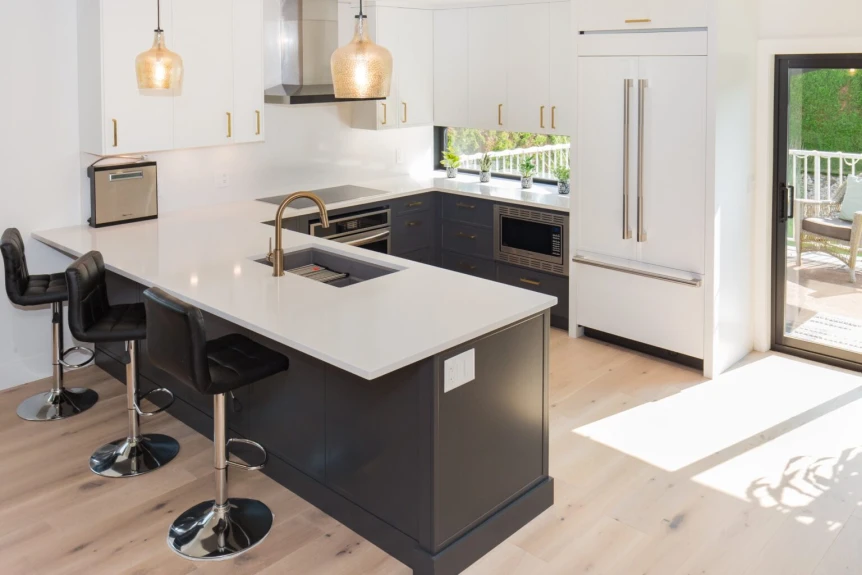 Modern small kitchen with black cabinets, white countertops, island seating, and natural light from patio doors