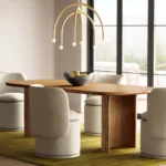 Modern dining room with oval wood table, cream upholstered chairs, and gold arch pendant light fixture