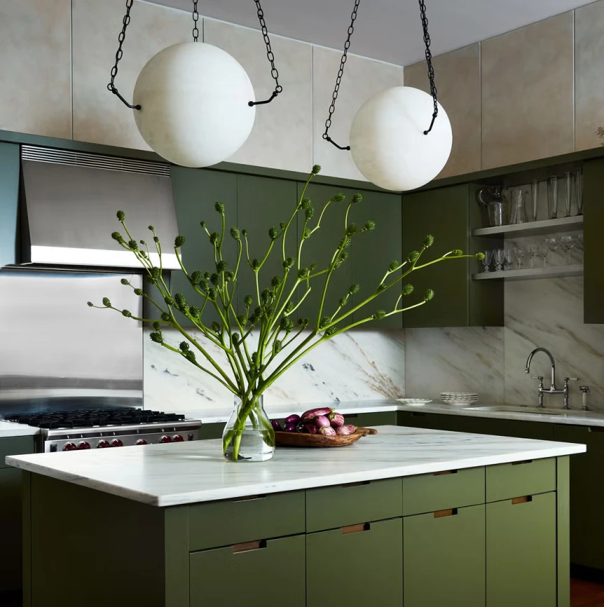Modern kitchen with olive green cabinets, white marble countertops, and spherical pendant lights