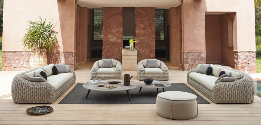 Luxury outdoor patio with woven wicker furniture, neutral cushions, and modern desert-inspired architecture