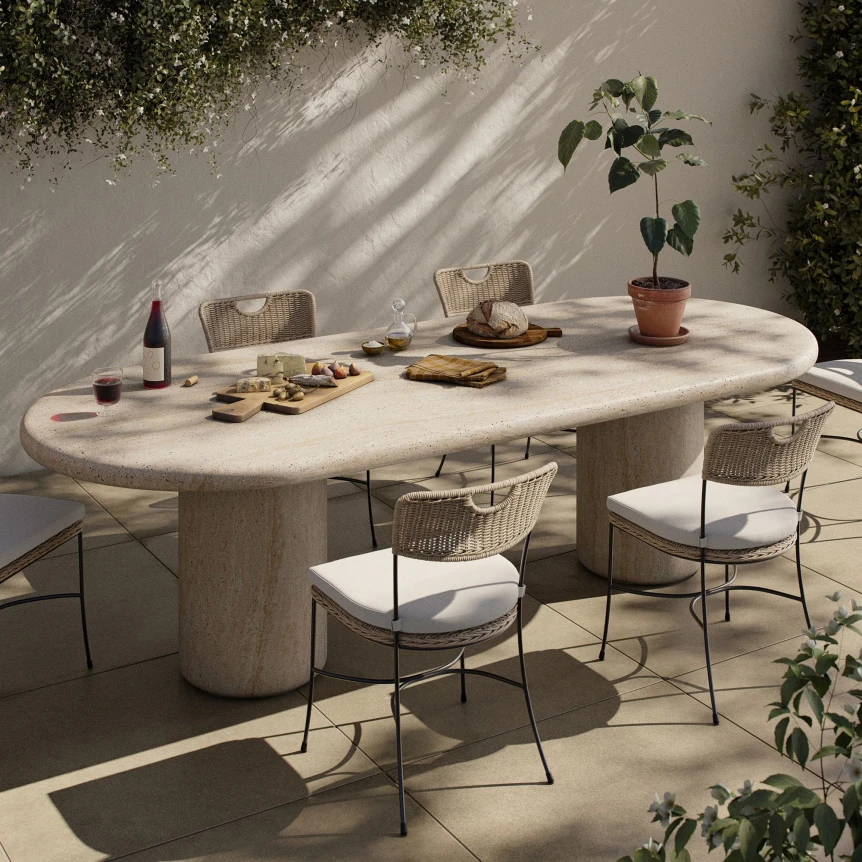 Oval concrete outdoor dining table with wicker chairs on sunny patio with plants and wine setup
