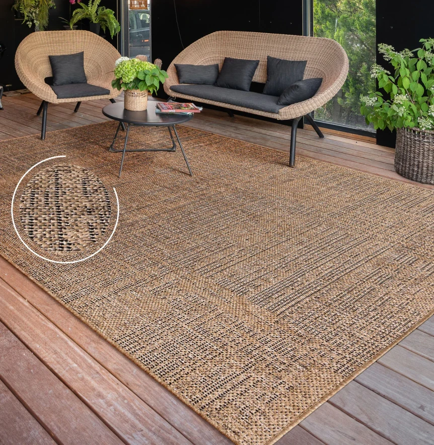 Natural jute outdoor rug on wooden deck patio with wicker furniture and black cushions