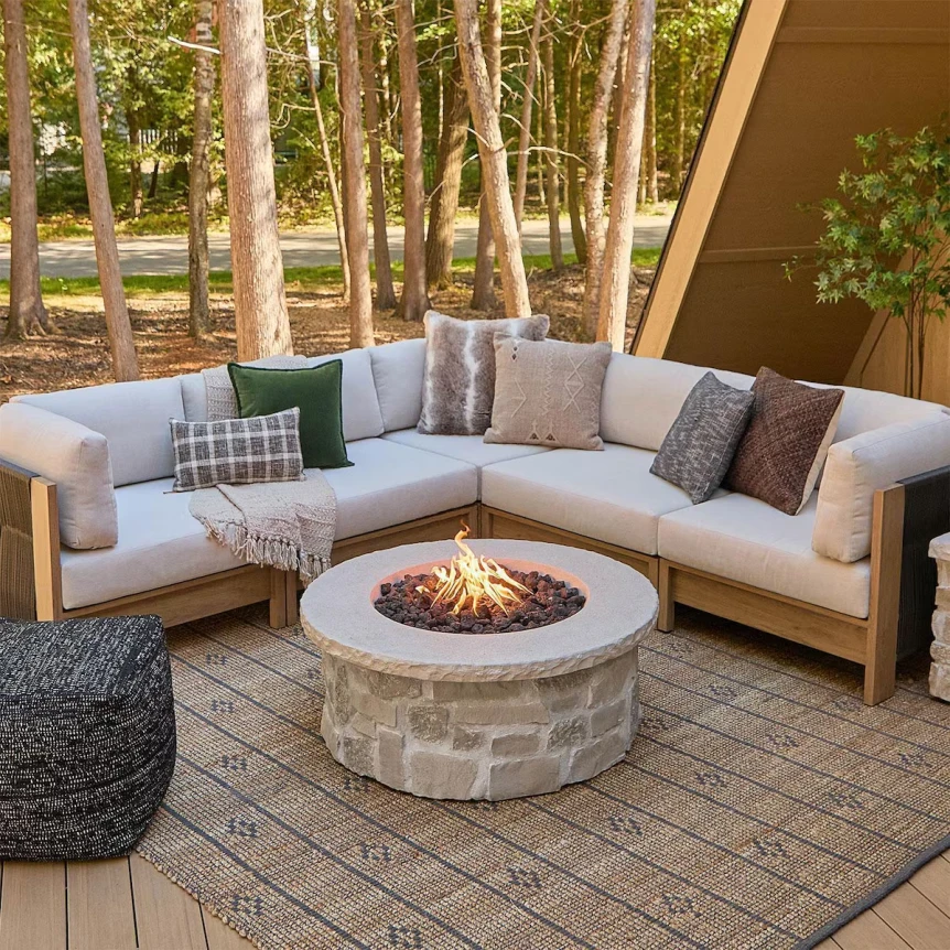 Outdoor patio with sectional sofa, decorative pillows, stone fire pit, and textured area rug under covered deck