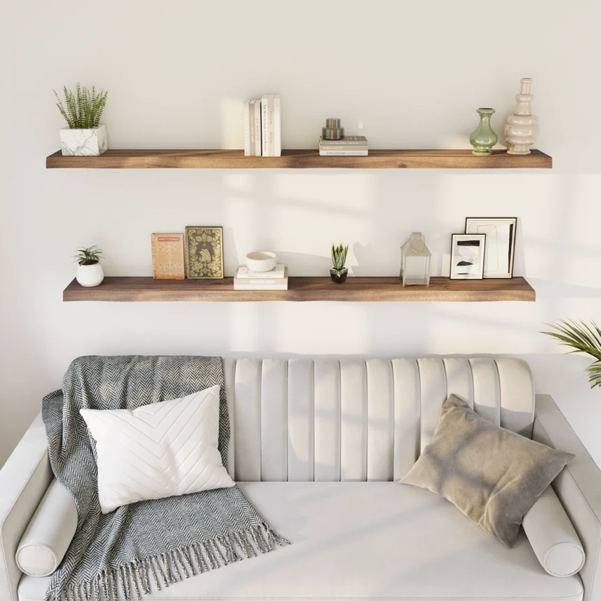 Modern living room with wooden floating shelves above gray velvet sofa displaying minimalist decor and plants