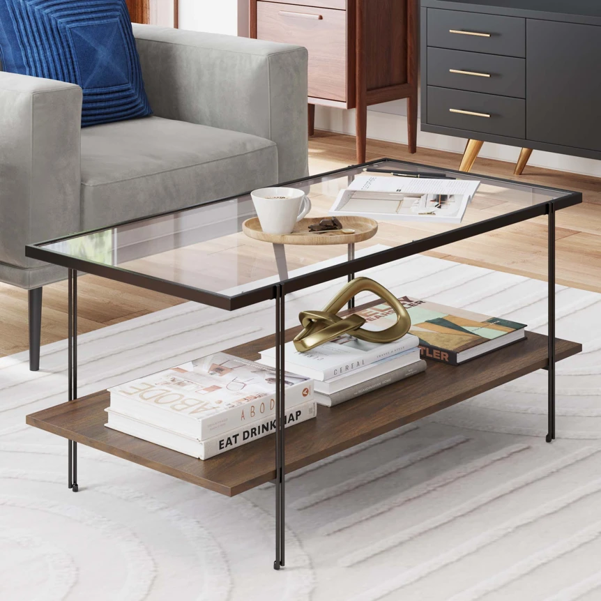Modern glass top coffee table with wood shelf and metal frame in contemporary living room setting