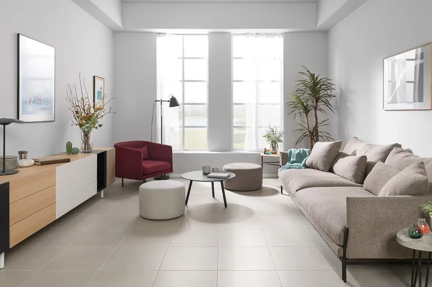 Modern living room with neutral palette, beige sofa, burgundy accent chair, and natural light from large windows