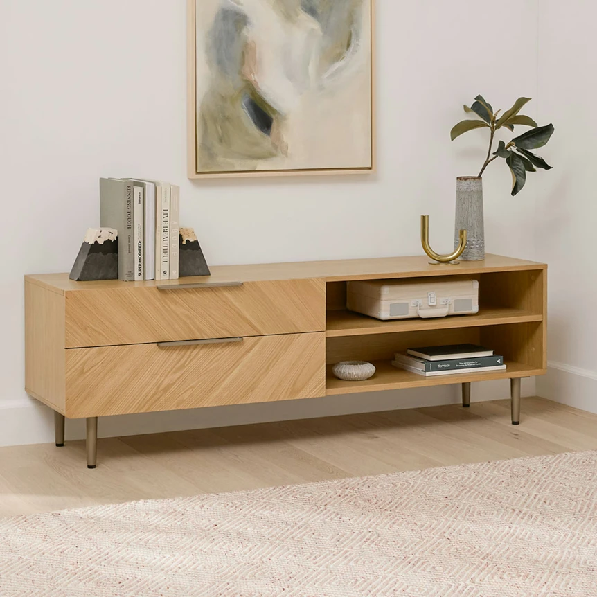 Modern oak TV stand with drawers and open shelving displaying books and decor in minimalist living room
