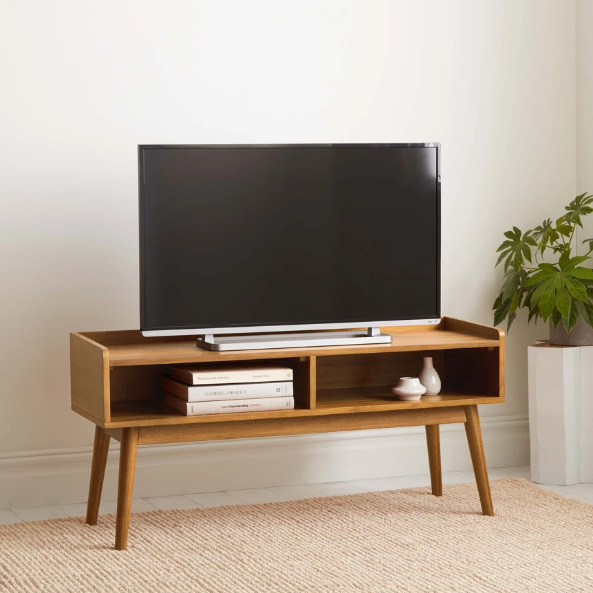 Mid-century modern wooden TV stand with open shelving and angled legs supporting flat screen television