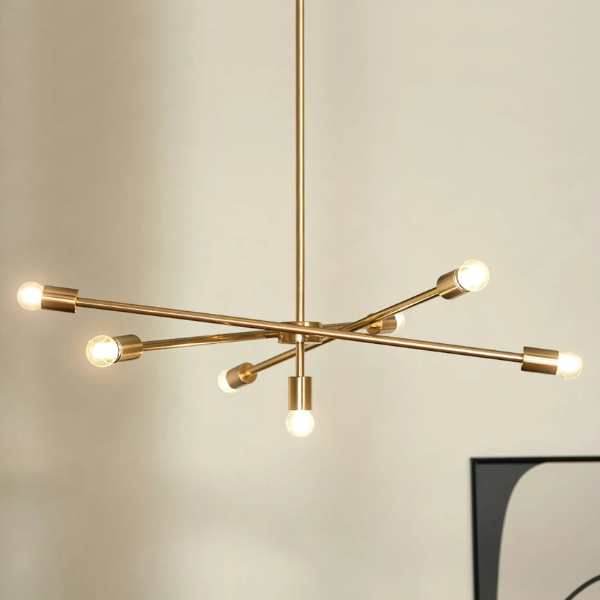 Modern gold brass sputnik chandelier with six arms and exposed bulbs hanging in minimalist living room
