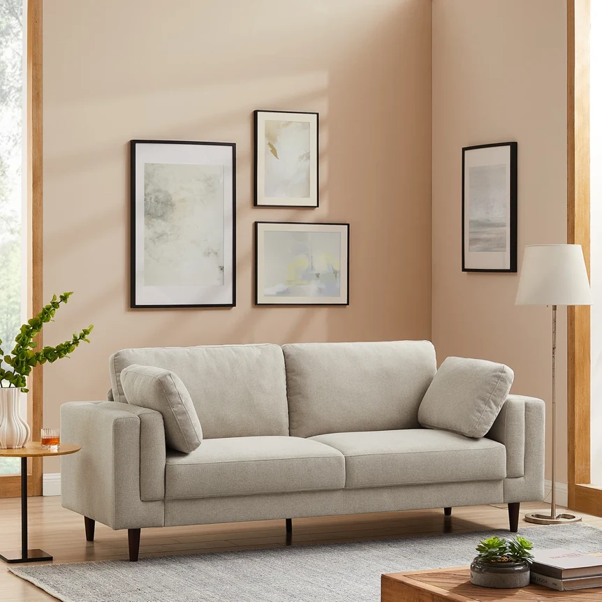 Modern beige sofa with clean lines in minimalist living room with framed artwork and warm lighting